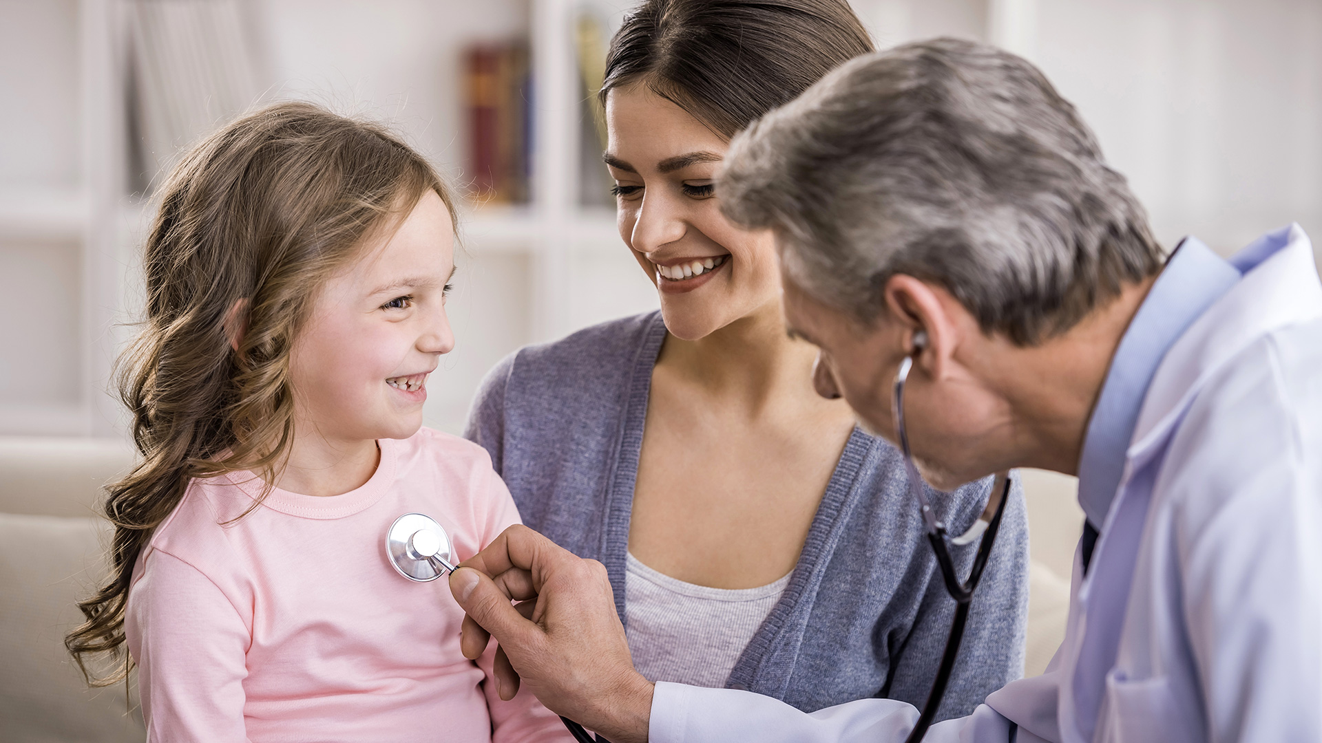 Uma menina sendo examinada por um médico com um estetoscópio